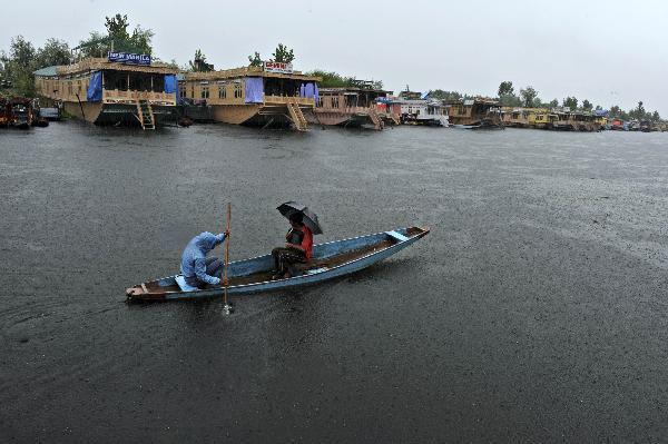 The local residents row a boat against the heavy rain, in Srinagar, the capital of Indian-controlled Kashmir, on August 6, 2010. At least 85 people were killed and scores injured on Friday after flash floods hit a major town in the mountainous area of Ladakh in Indian-controlled Kashmir, officials said. [Xinhua]