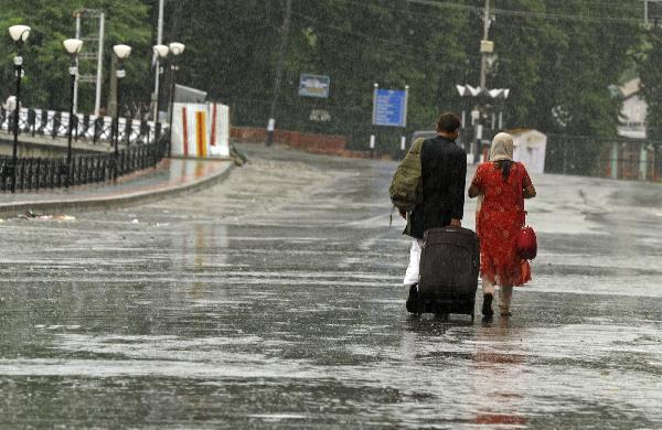 A couple wade through the flooded street in in Srinagar, the capital of Indian-controlled Kashmir, on August 6, 2010. At least 85 people were killed and scores injured on Friday after flash floods hit a major town in the mountainous area of Ladakh in Indian-controlled Kashmir, officials said.[Xinhua]