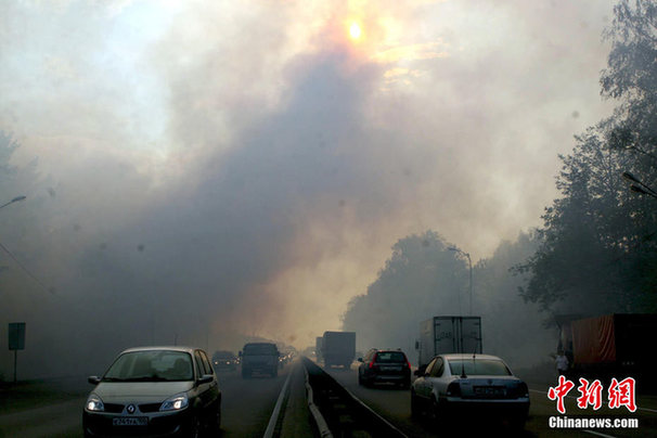 Cars drive through a heavy smog caused by peat fires in nearby forests in Moscow, August 6, 2010. [Chinanews]