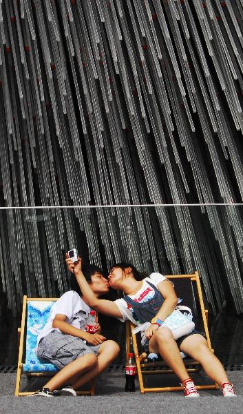 People rest on chaise longues near the Britain Pavilion in 2010 World Expo Site in Shanghai, China, Aug. 6, 2010. Painted chaise longues designed by famous designers from Britain and China were brought to Expo recently. [Xinhua]