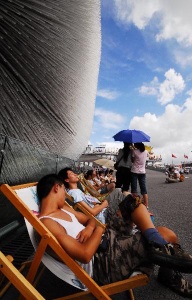 People rest on chaise longues near the Britain Pavilion in 2010 World Expo Site in Shanghai, China, Aug. 6, 2010. Painted chaise longues designed by famous designers from Britain and China were brought to Expo recently. [Xinhua]