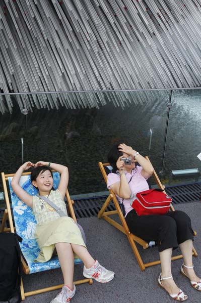 People rest on chaise longues near the Britain Pavilion in 2010 World Expo Site in Shanghai, China, Aug. 6, 2010. Painted chaise longues designed by famous designers from Britain and China were brought to Expo recently. [Xinhua]