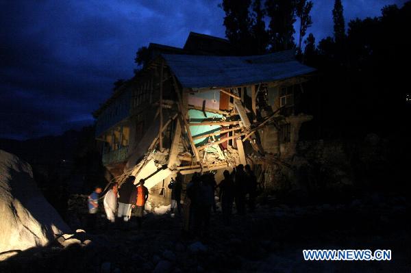 People stand by the debris of a damaged house in Kargil some 235 kilometers from Leh in Ladakh, India-controlled Kashmir, August 6, 2010. [Xinhua]