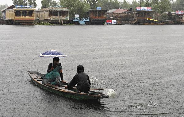 The local residents row a boat against the heavy rain, in Srinagar, the capital of Indian-controlled Kashmir, on August 6, 2010. [Xinhua]