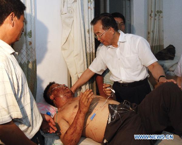 Chinese Premier Wen Jiabao(R) visits an injured person who got hurt during the landslides at a hospital in Zhouqu County, Gannan Tibetan Autonomous Prefecture in northwest China&apos;s Gansu Province, Aug. 8, 2010. [Xinhua] 