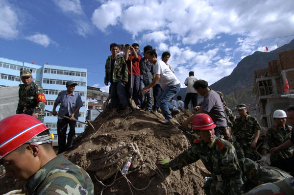 Armed police officers and local residents search through rubble on Sunday to look for survivors of a landslide triggered by floods in Zhouqu county, Northwest China&apos;s Gansu province. [Xinhua]