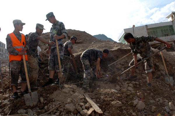  Armed police officers search through rubble on Sunday to look for survivors of a landslide triggered by floods in Zhouqu county, Northwest China&apos;s Gansu province. Thousands of soldiers, armed police officers and firefighters rushed to the area to help in the rescue operation on Aug 8, 2010. [Xinhua]