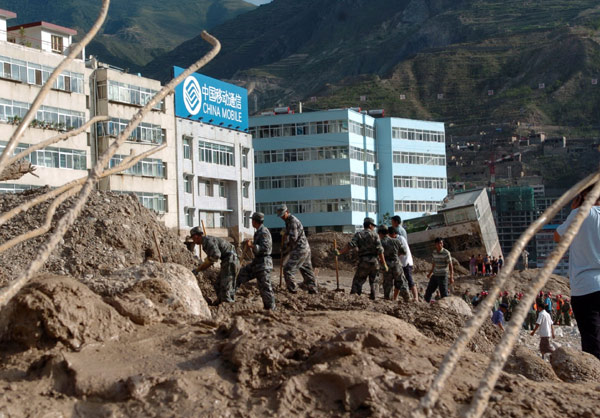 Armed police officers and local residents search through rubble on Sunday to look for survivors of a landslide triggered by floods in Zhouqu county, Northwest China&apos;s Gansu province. Thousands of soldiers, armed police officers and firefighters rushed to the area to help in the rescue operation on Aug 8, 2010. [Xinhua]