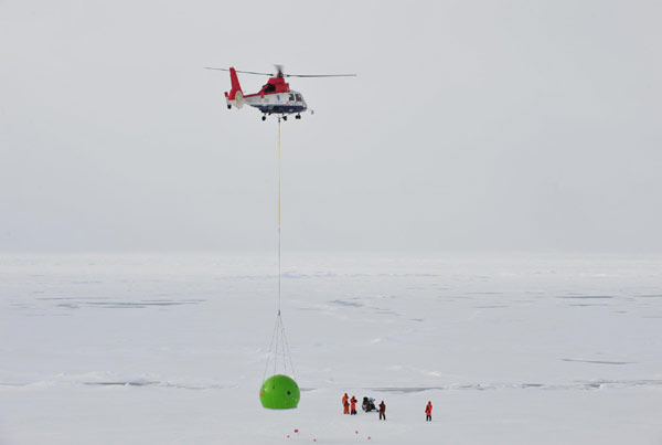 A helicopter carries an apple-like house, built to defend against polar bears, to the researchers&apos; working site, Aug 8, 2010. The Chinese expedition team built a fixed ice station Sunday for their 15-day expedition in the Arctic Ocean. The station lies at 86 degrees and 55 minutes north latitude, 178 degrees and 53 minutes west longitude. [Xinhua]
