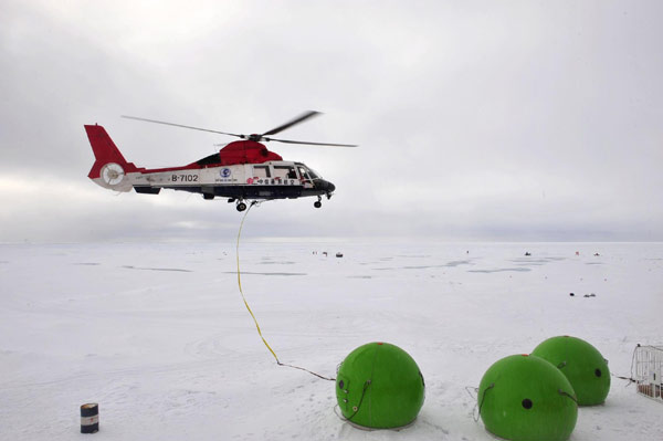 A helicopter loads an apple-like house, built to defend against polar bears, to the researchers&apos; working site, Aug 8, 2010. The Chinese expedition team built a fixed ice station Sunday for their 15-day expedition in the Arctic Ocean. [Xinhua]