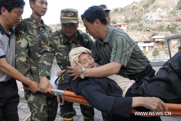 Rescuers carry a 78-year-old survivor in landslide-hit Zhouqu County, Gannan Tibetan Autonomous Prefecture in northwest China&apos;s Gansu Province, Aug. 8, 2010. Soldiers sent by the Lanzhou Military Area Command of the Chinese People&apos;s Liberation Army have saved 9 people from rain-triggered landslides in Zhouqu County. [Xinhua]