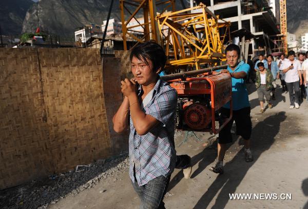  Local residents carry rescue equipment in landslide-hit Zhouqu County, Gannan Tibetan Autonomous Prefecture in northwest China&apos;s Gansu Province, Aug. 8, 2010. [Xinhua]