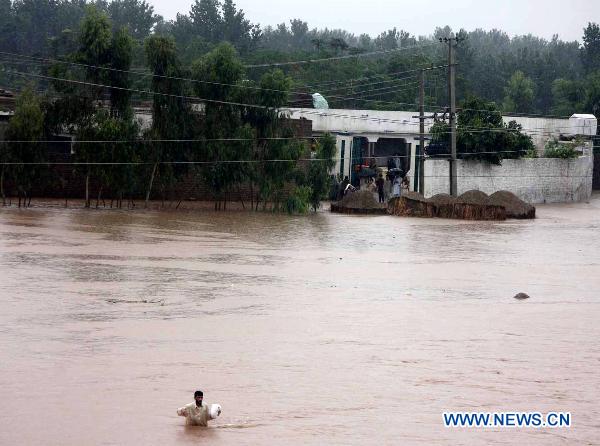 A Pakistani man walks through a flooded street in northwest Pakistan&apos;s Charsadda, on Aug. 8, 2010. The worst floods in Pakistan since 1929 have left more than 14 million people in need of emergency assistance and at least 1,600 people killed.[Saeed Ahmad/Xinhua]