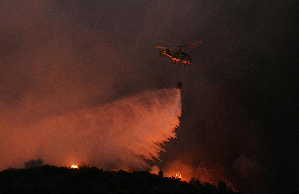 A helicopter drops water over a forest fire in Carvalhal, near Sao Pedro do Sul August 8, 2010. More than 700 firefighters and soldiers are trying to extinguish dozens of forest fires in Portugal after temperatures rose up to 40 degree Celsius in several areas of the country.[Xinhua]