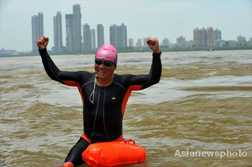 A fan of swimming, Bao Zhengbin greets supporters during his drill in the Yangtze River at Wuhan city, Central China’s Hubei province on July 1, 2010. [Asianewsphoto] 