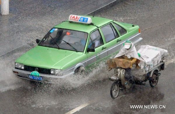 Vehicles run on a flooded street in Zhengzhou, capital of central China&apos;s Henan Province, Aug. 9, 2010. Zhengzhou encountered a heavy rainstorm Monday afternoon. [Xinhua] 