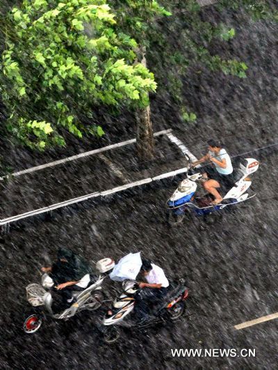 Residents ride motorbikes in rainstorm on a street in Zhengzhou, capital of central China&apos;s Henan Province, Aug. 9, 2010. Zhengzhou encountered a heavy rainstorm Monday afternoon. [Xinhua] 