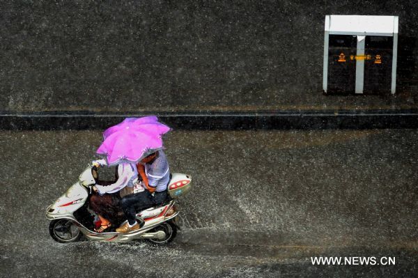 Two residents ride a motorbike in rainstorm on a street in Zhengzhou, capital of central China&apos;s Henan Province, Aug. 9, 2010. Zhengzhou encountered a heavy rainstorm Monday afternoon. (Xinhua/Wang Song) (zn) 