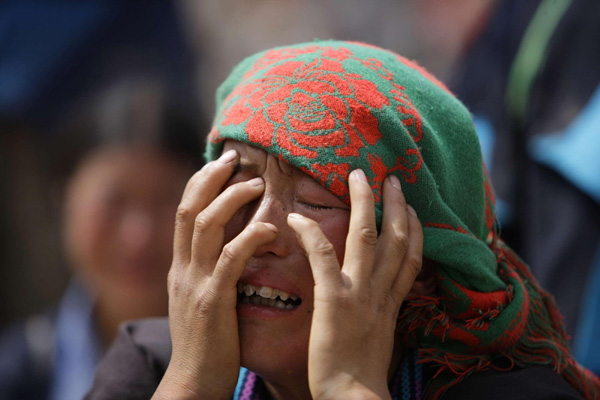 A woman cries before the debries of her house in the landslide-hit Zhouqu County of Gannan Tibetan Autonomous Prefecture, Gansu Province August 9, 2010. [Xinhua]