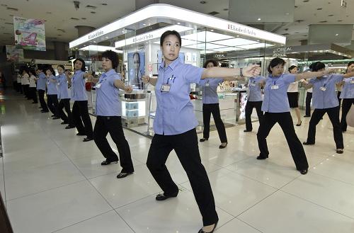 Sales staff at Xidan shopping center do radio gymnastic exercises before opening for business in downtown Beijing on Aug 8, 2010. [Xinhua] 