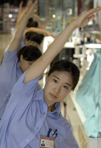 Sales staff at Xidan shopping center do radio gymnastic exercises before opening for business in downtown Beijing on Aug 8, 2010. [Xinhua] 