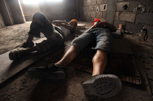 Two students have a nap after work at the construction site at North University of Nationalities in Yinchuan, Northwest China&apos;s Ningxia Hui autonomous region, Aug 9, 2010. [Xinhua]