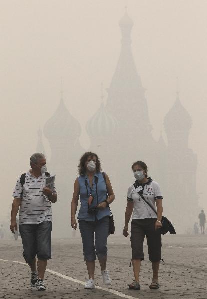 Tourists, wearing masks to protect themselves from the smell of heavy smog caused by peat fires in nearby forests, walk along Red Square in central Moscow August 9, 2010. [Xinhua]