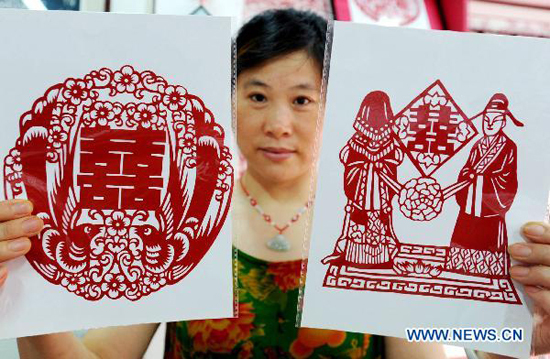 A woman shows paper-cuttings made by local folk artists to celebrate the upcoming 'Qixi', the Chinese Valentine's Day, in Suzhou, east China's Jiangsu Province, Aug. 8, 2010.