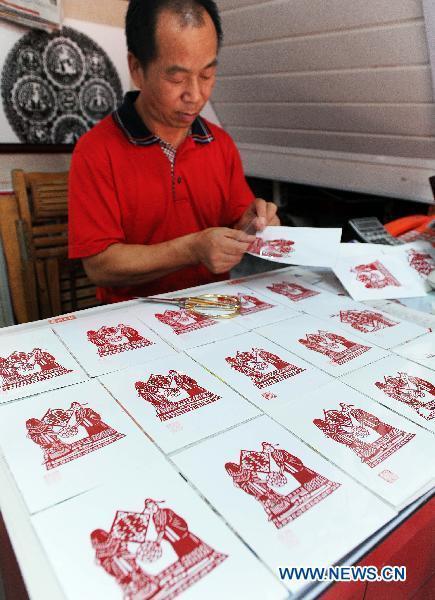 A folk artist makes paper-cuttings to celebrate the upcoming 'Qixi', the Chinese Valentine's Day, in Suzhou, east China's Jiangsu Province, Aug. 8, 2010.