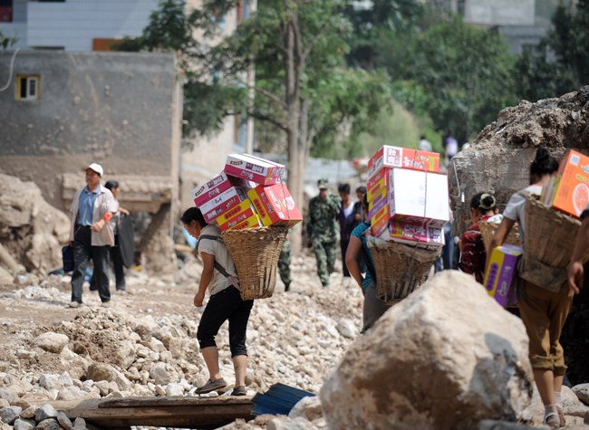 Residents of Yuanyue Village carry home relief materials in the landslides-hit Zhouqu County, Gannan Tibetan Autonomous Prefecture in northwest China&apos;s Gansu Province, Aug. 10, 2010. The rain-triggered landslide has caused 337 people dead and 1,148 others missing till 2:00 p.m. (0600 GMT) Monday. [Xinhua]