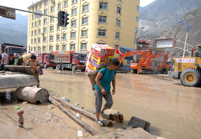 A woman carries home relief materials in the landslides-hit Zhouqu County, Gannan Tibetan Autonomous Prefecture in northwest China&apos;s Gansu Province, Aug. 10, 2010. The rain-triggered landslide has caused 337 people dead and 1,148 others missing till 2:00 p.m. (0600 GMT) Monday. [Xinhua]