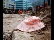 A pink hat lies in the mud, Aug 10, 2010. [Xinhua]