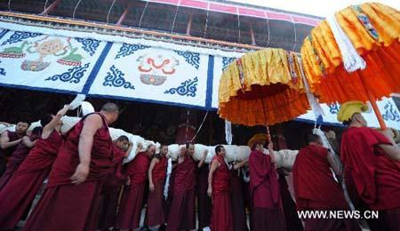 Lamas carry a huge-sized Buddha Thangka painting to the site where the Buddha Thangka painting unfolding ceremony is held in Zhaibung Monastery on the outskirts of Lhasa, capital of southwest China's Tibet Autonomous Region, on Aug. 10, 2010. 