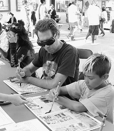 A father and his son learn to write Chinese calligraphy in the Confucius Institute, University of California in Los Angeles under the guidance of teachers, on August 7, 2010. Activities are held in Chinatown of Los Angeles every Saturday in August, including cultural performances, lectures on Chinese culture, and Chinese food cooking show.