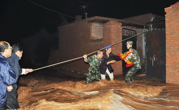 Armed Police officers rescue residents in Wuzhong city, Ningxia Hui autonomous region, from their flooded homes on Aug. 11, 2010. Flooding triggered by torrential rain hit four places in the city, leaving at least 280 houses damaged and more than 1,000 people trapped. [Xinhua]