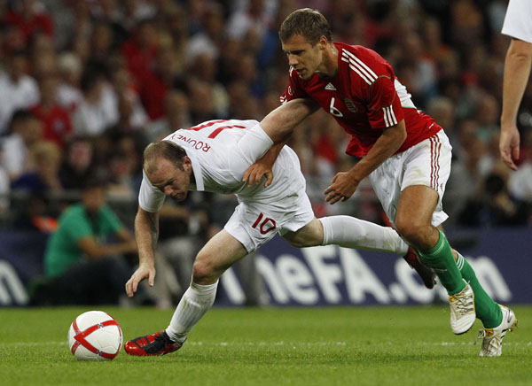 England's Wayne Rooney (L) is challenged by Hungary's Krisztian Vadocz during their international friendly soccer match at Wembley Stadium in London August 11, 2010. (Xinhua/Reuters Photo)