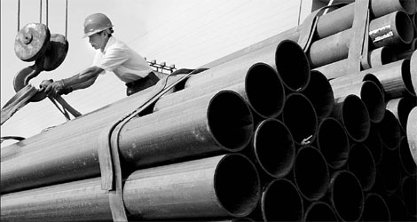 A worker moves steel piping at a distribution center in Nantong, Jiangsu province. [China Daily]