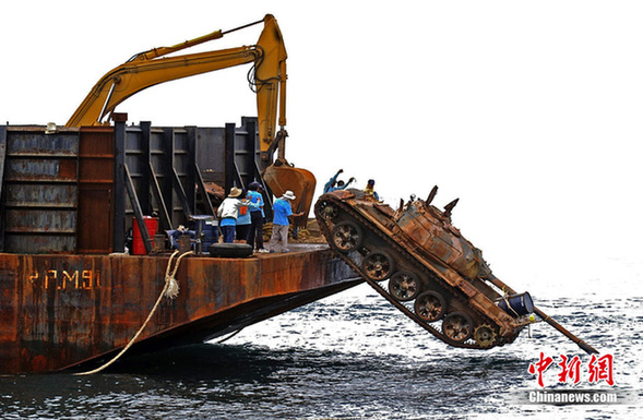 Workers push an old tank from a ship into the sea off Narathiwat province, southern Thailand Monday, Aug. 9, 2010. Twenty five junk tanks were transported from Bangkok and dumped at sea in the Gulf of Thailand to help forming artificial reefs and providing home for fish. [chinanews.com]