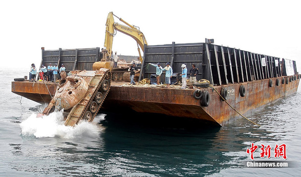 Workers push an old tank from a ship into the sea off Narathiwat province, southern Thailand Monday, Aug. 9, 2010. [chinanews.com]