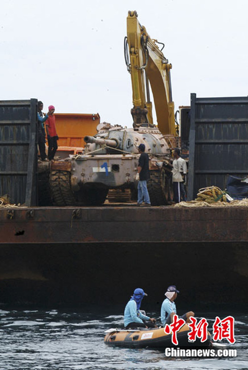 Workers prepare to push an old tank from a ship into the sea off Narathiwat province, southern Thailand Monday, Aug. 9, 2010. [chinanews.com]