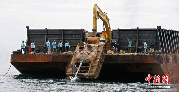 Workers push an old tank from a ship into the sea off Narathiwat province, southern Thailand Monday, Aug. 9, 2010. [chinanews.com]