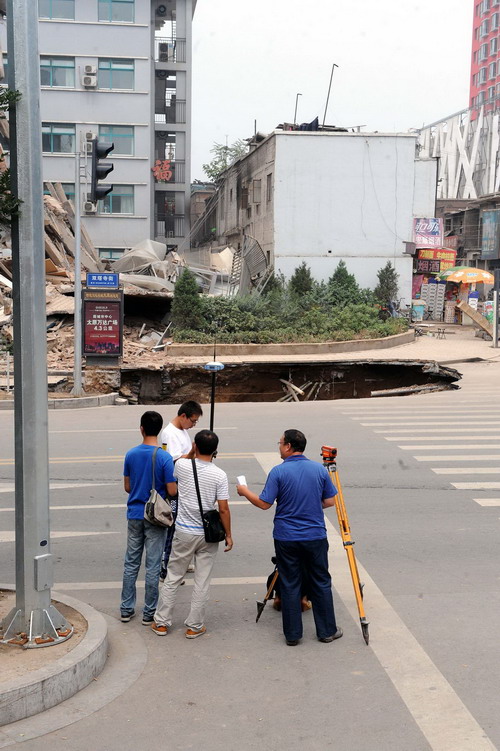 Staffers from Taiyuan Institute of Municipal Engineering Design and Research examine the road near the collapsed building at Shanxi Provincial People&apos;s Hospital on Shuangta East Street in Taiyuan, capital city of North China&apos;s Shanxi province on August 12, 2010.[Xinhua]