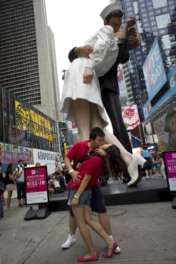 A couple kisses beside a statue in Times Square, New York city, the United States August 12, 2010. A 26-feet-tall statute of a sailor kissing a nurse, which is modeled on a famous photograph that became a symbol of the Times Square celebrations at the end of World War II, was installed on 44th Street and Broadway Thursday.[Xinhua] 