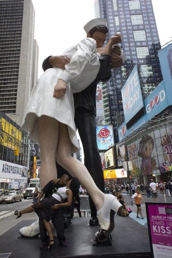 A couple kisses beside a statue in Times Square, New York city, the United States August 12, 2010.[Xinhua] 