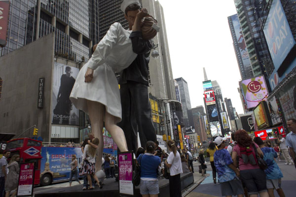 A couple kisses beside a statue in Times Square, New York city, the United States August 12, 2010. [Xinhua]