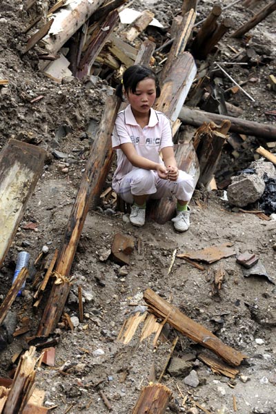 Mou Rui, a 10-year-old girl, sits at the roof of her buried house to waits for information of her missing mother in the landslide-hit Zhouqu County, Gannan Tibetan Autonomous Prefecture in northwest China&apos;s Gansu Province, Aug. 12, 2010. [Xinhua]