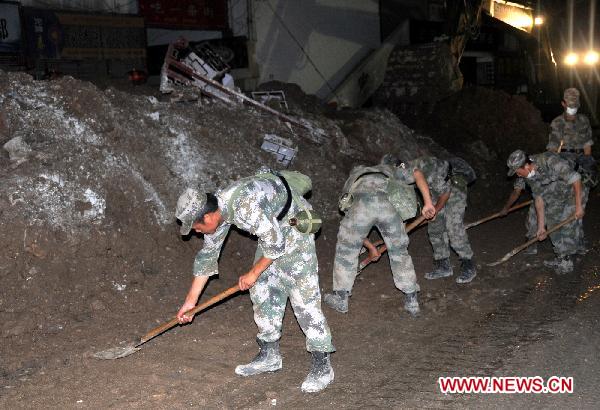 Soldiers clear road surface in landslide-hit Zhouqu County, northwest China's Gansu Province, early Aug. 13, 2010. Rescuers are busy clearing away ruins and garbage after the landslide. All the ruins and garbage will be dealt with epidemic prevention measures.