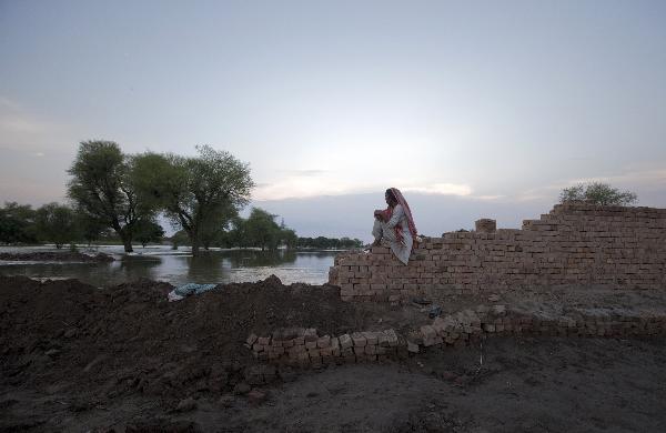 A woman watches flood waters rise from the outside wall of her compound in Pakistan's Muzaffargarh district in Punjab province August 13, 2010. Disease outbreaks pose grave new risks to victims of Pakistan's worst floods in decades, aid agencies said on Friday, potentially hindering already complicated relief efforts as desperation grows.