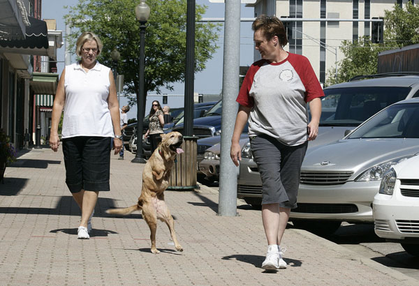 The two-legged dog 'Faith' walks with her master in the street.