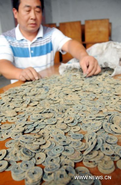 A staff member of the Shahe Administration of Cultural Heritage shows antique coins dating back to ancient China's Tang Dynasty (618-907) in Shahe City, north China's Hebei Province, Aug. 13, 2010. Archeologists recently unearthed about 17,000 antique coins of the Tang Dynasty from a construction site in Shahe.